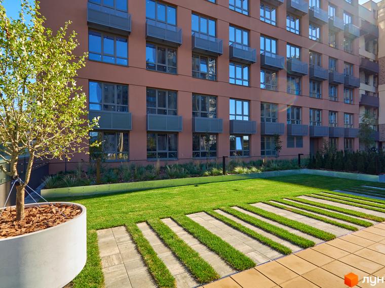 Зовнішній вигляд будинку на Вавилових з терасами та великими вікнами. Зелена прибудинкова територія з газоном та доріжками.