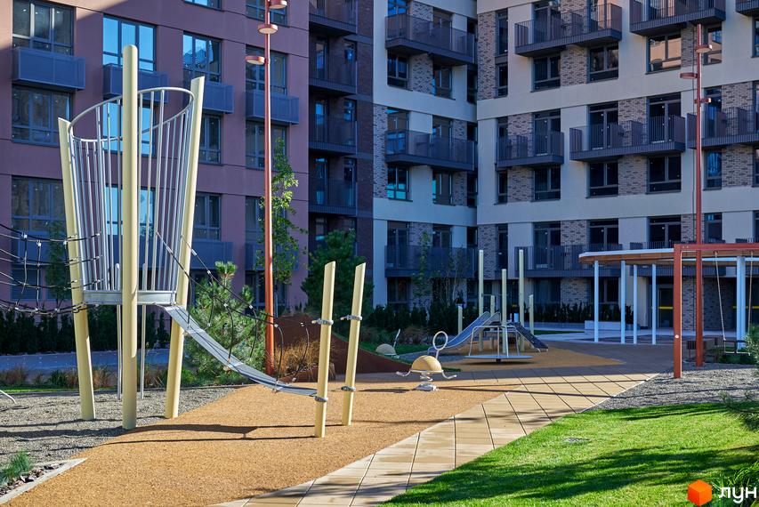 Будинок на Вавилових: багатоповерхові будівлі з балконами та різнокольоровими фасадами. Дитячий майданчик з ігровим обладнанням та зеленими зонами.