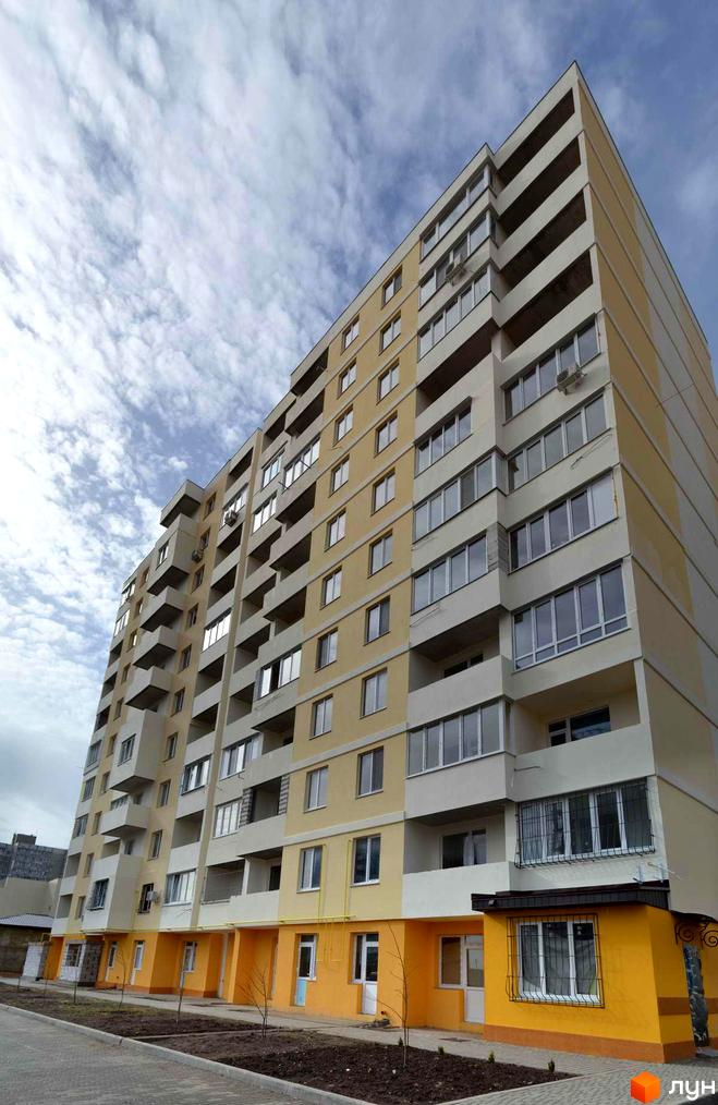 Житловий комплекс Суворівський 2. Висотна будівля з жовтим фасадом та балконами. На прибудинковій території висаджені дерева та є тротуар.