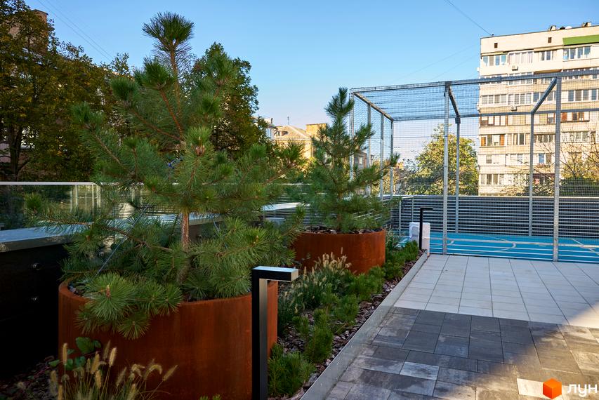 Будинок на Вавилових: багатоповерховий житловий будинок та облаштована прибудинкова територія зі спортивним майданчиком і озелененням.