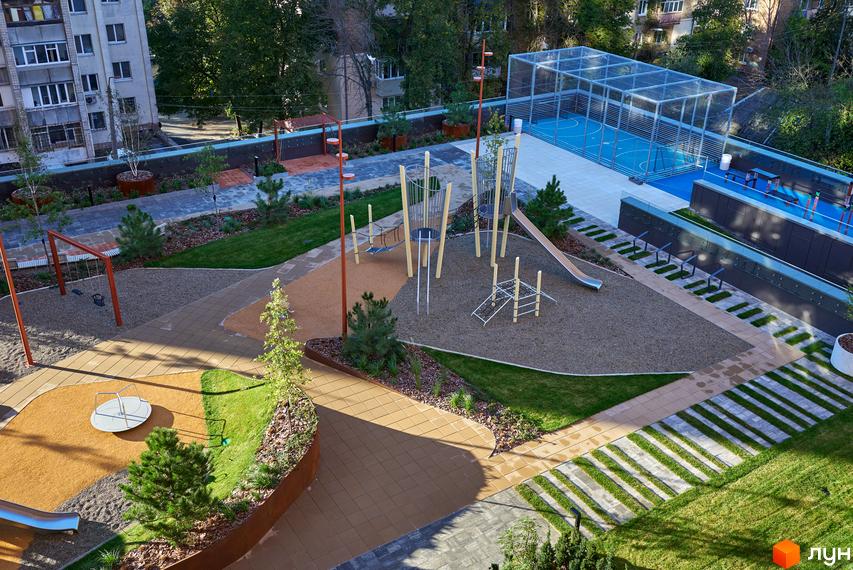 Багатоповерховий житловий будинок на Вавилових та його велика прибудинкова територія з дитячими майданчиками, спортивним полем та зонами відпочинку.