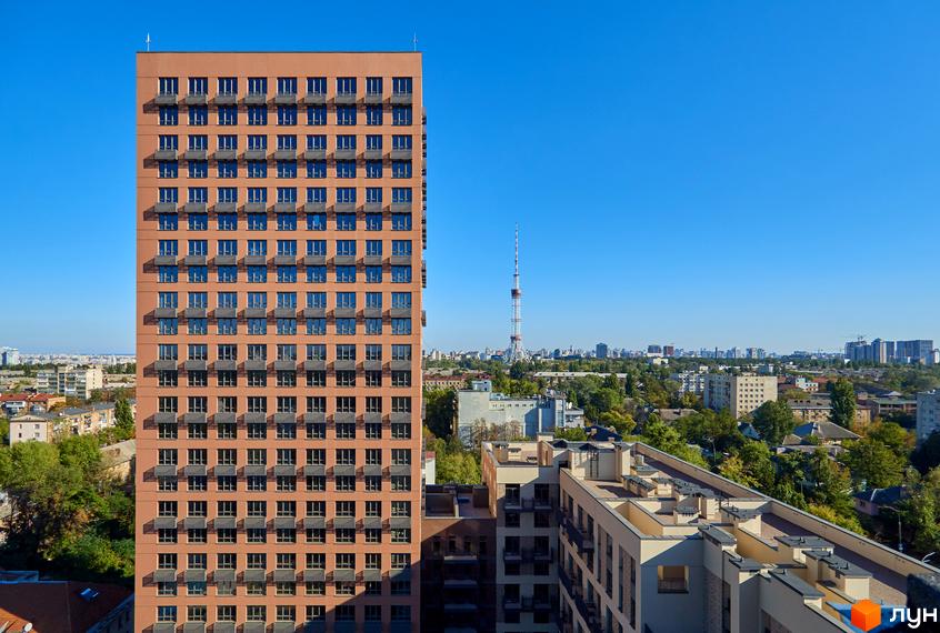 Висотна будівля житлового комплексу Будинок на Вавилових з великою кількістю вікон та балконів. Навколо будинку розташовані інші будівлі та зелені насадження.