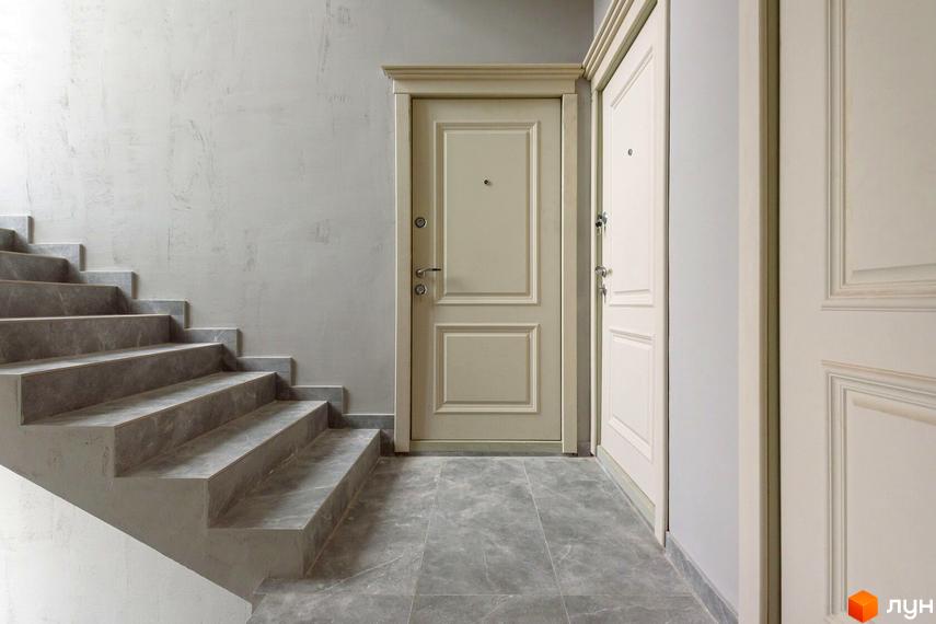 Клубний будинок „Кагарлицький“: сходова клітка з сірими сходами та дверима в спокійних тонах. Ознайомтеся з новобудовою на нашому сайті.