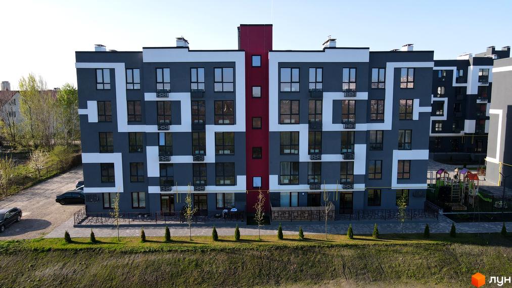 Новобудова ЖК Рідний-2 з сірим фасадом та білими геометричними візерунками, поруч дитячий майданчик.