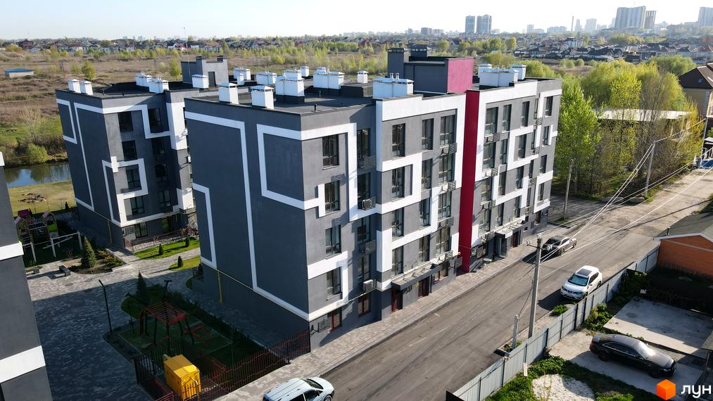 Житловий комплекс Рідний-2 має сіро-білий фасад з червоною смугою. На прибудинковій території є дитячий майданчик та парковка.