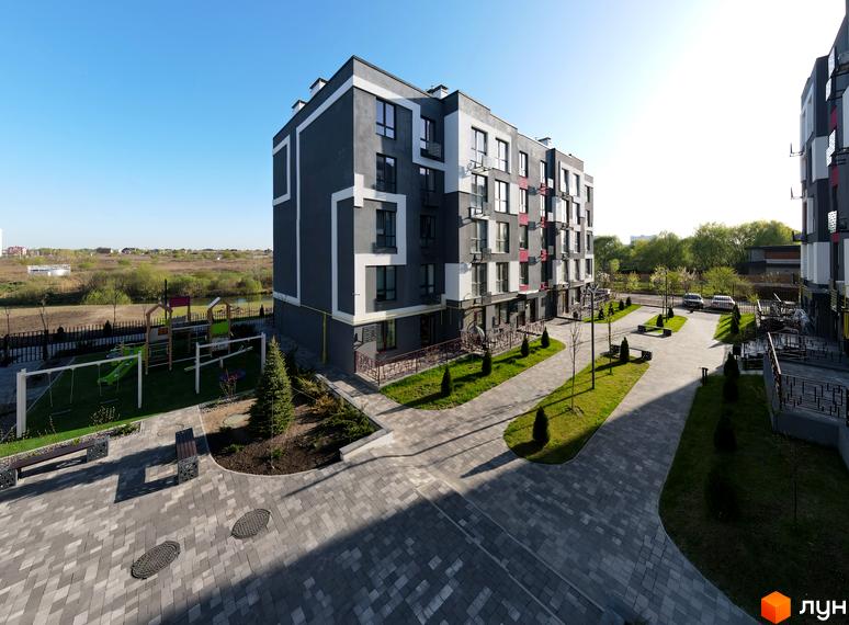 Зовнішній вигляд новобудови ЖК Рідний-2 з сірими фасадами та білими декоративними елементами, поруч дитячий майданчик та доглянута прибудинкова територія.