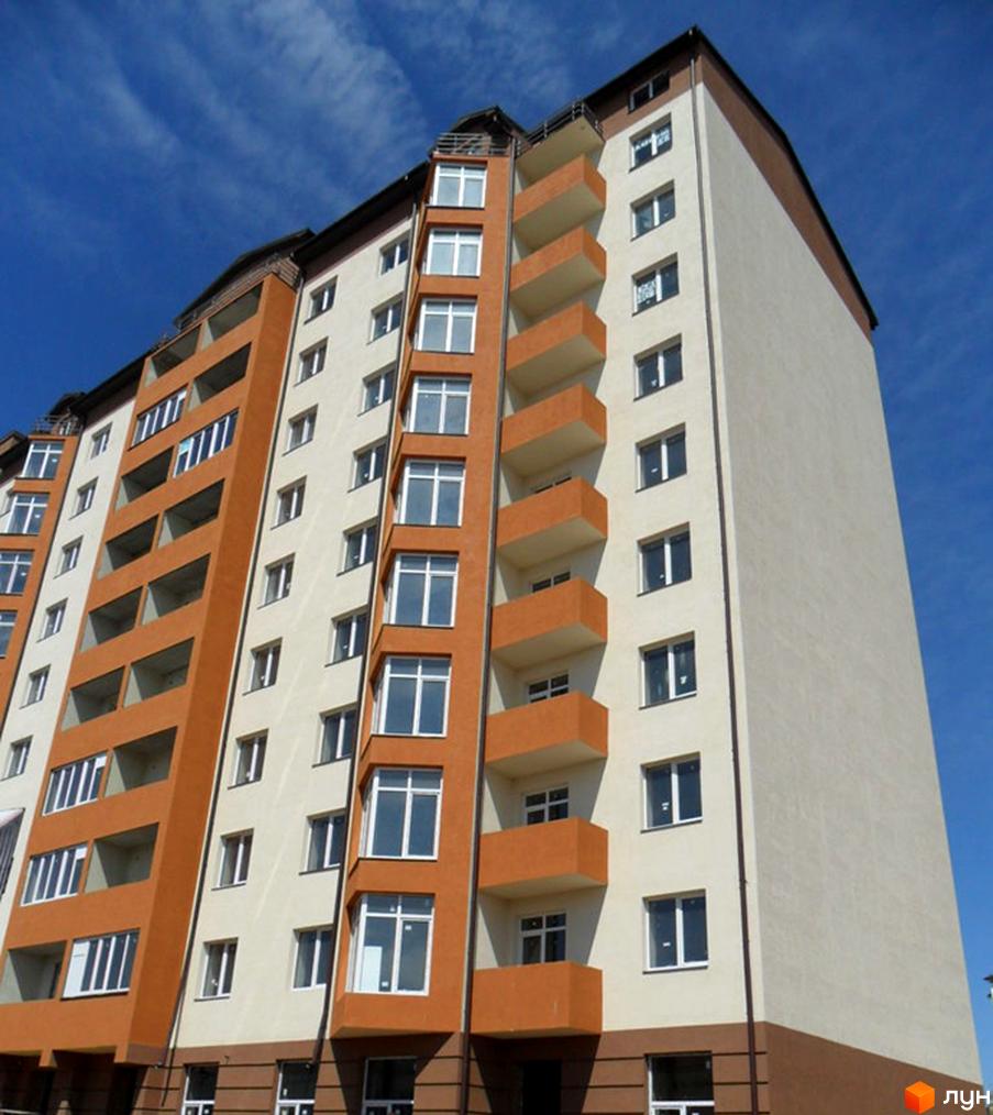 Зображення фасаду житлового будинку на вулиці Стуса / Миколайчука. Багатоповерхівка з балконами та великими вікнами на фоні блакитного неба.