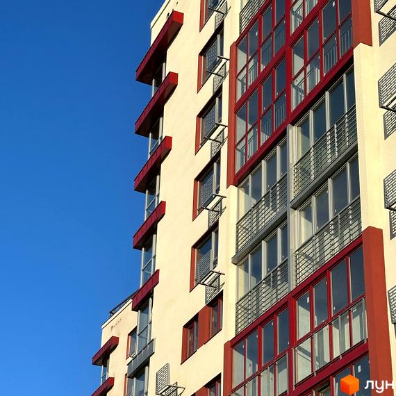 Зображення фасаду житлового комплексу Європейський з вікнами та балконами на фоні блакитного неба.