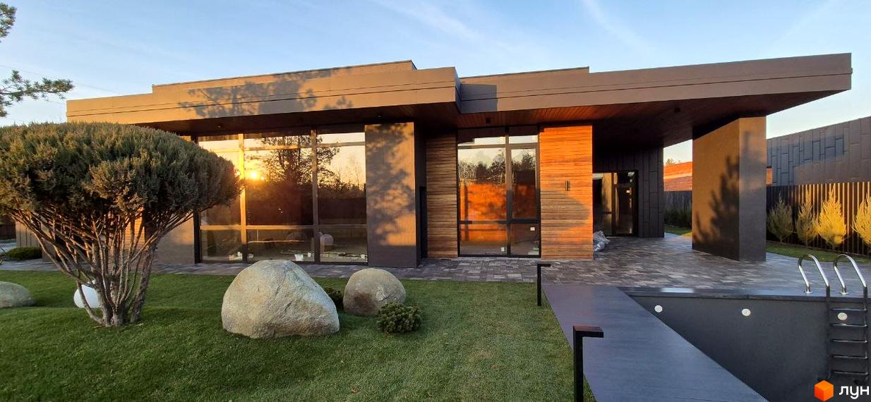 Котеджне містечко КМ Sobi Life: сучасний будинок з великими вікнами та дерев'яними елементами, доглянута прибудинкова територія з газоном та басейном.