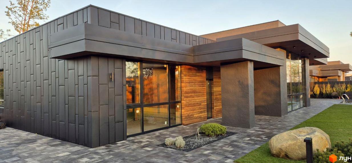 Котеджне містечко КМ Sobi Life: сучасний будинок з панорамними вікнами та дерев'яним оздобленням, доглянута прибудинкова територія з газоном та великим каменем.