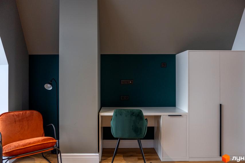 Інтер'єр кімнати з кріслом, робочим столом та шафою в житловому комплексі AMA FAMILY RESORT.