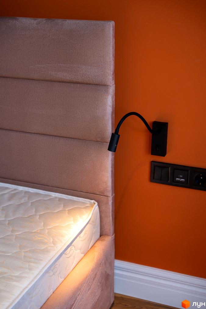 Сучасний інтер'єр спальні з ліжком та приліжним світильником на помаранчевій стіні.