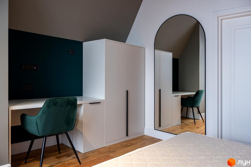 Сучасний інтер'єр спальні з робочою зоною та великою шафою. Стильні меблі та дзеркало створюють затишну атмосферу.