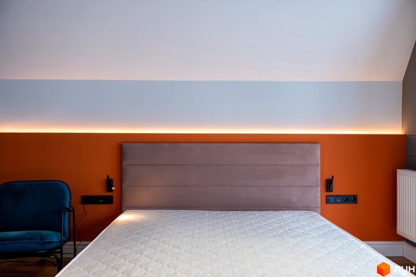 Спальня з ліжком та узголів'ям у житловому комплексі AMA FAMILY RESORT. На стіні за ліжком розташована помаранчева панель з підсвічуванням.