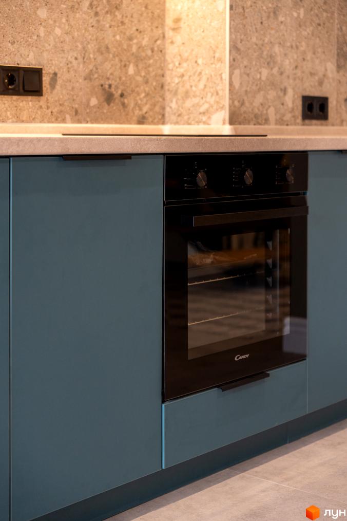 Сучасна кухня з вбудованою технікою Candy та сірим фартухом з кам'яною текстурою.