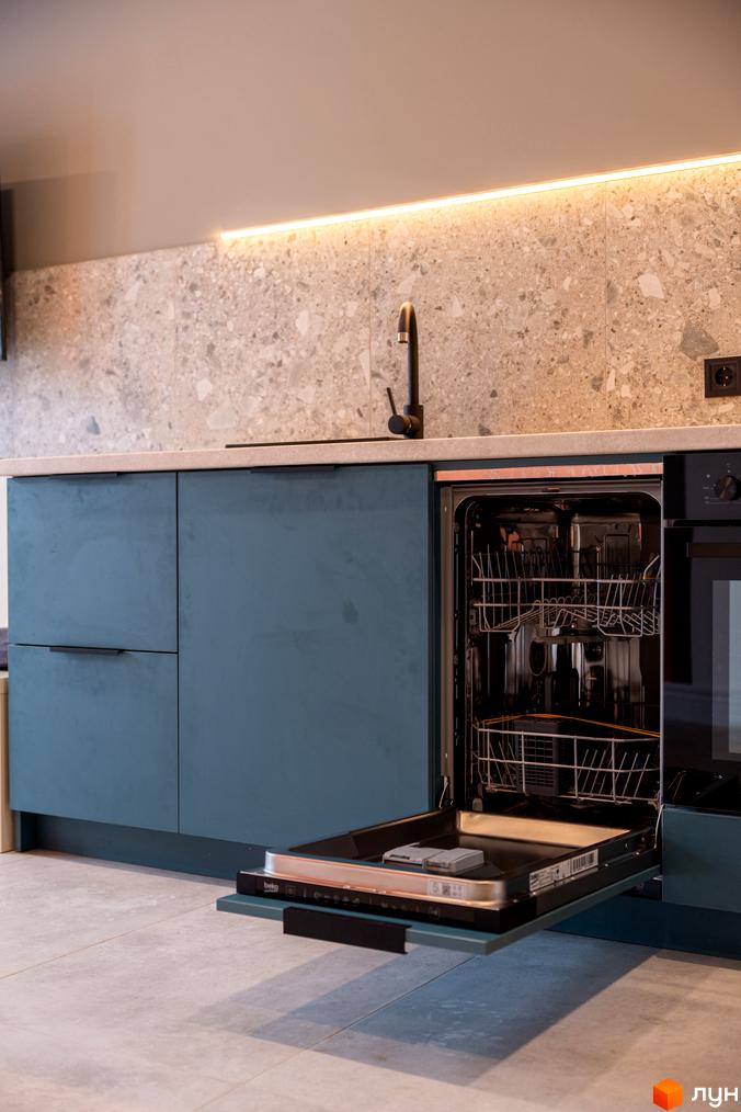 Сучасна кухня з вбудованою технікою, включаючи посудомийну машину з відкритим фасадом та стильними синіми шафами.