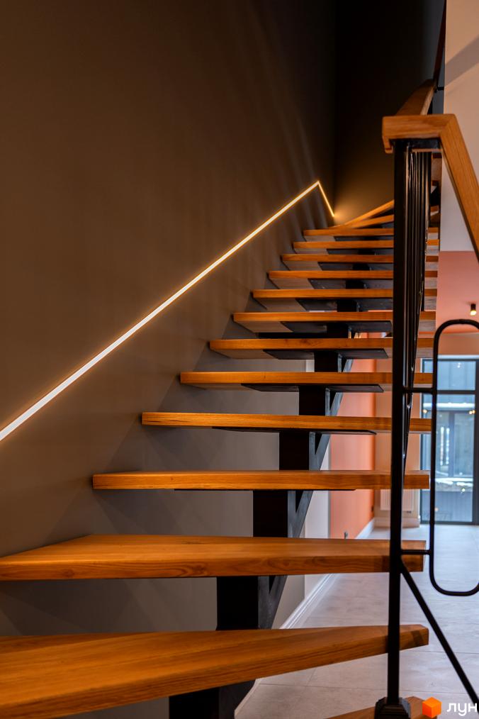 Сучасні дерев'яні сходи з підсвічуванням у житловому комплексі AMA FAMILY RESORT. Стильний дизайн сходів з чорними металевими елементами.