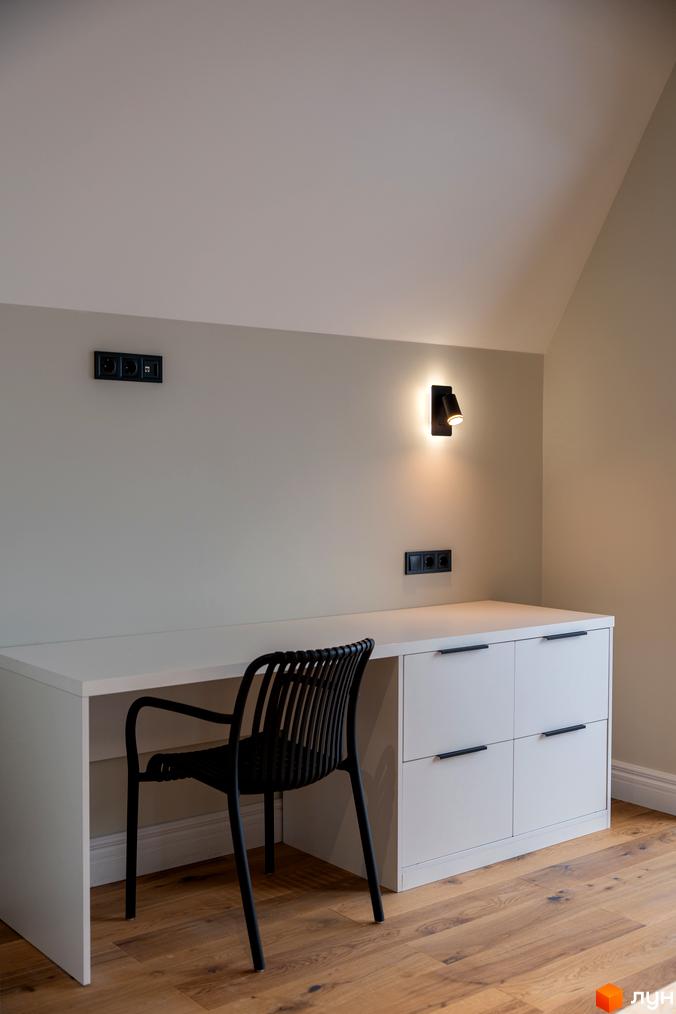 Сучасний інтер'єр кімнати з білим столом, чорним кріслом та бра на стіні. AMA FAMILY RESORT – це новий житловий комплекс.