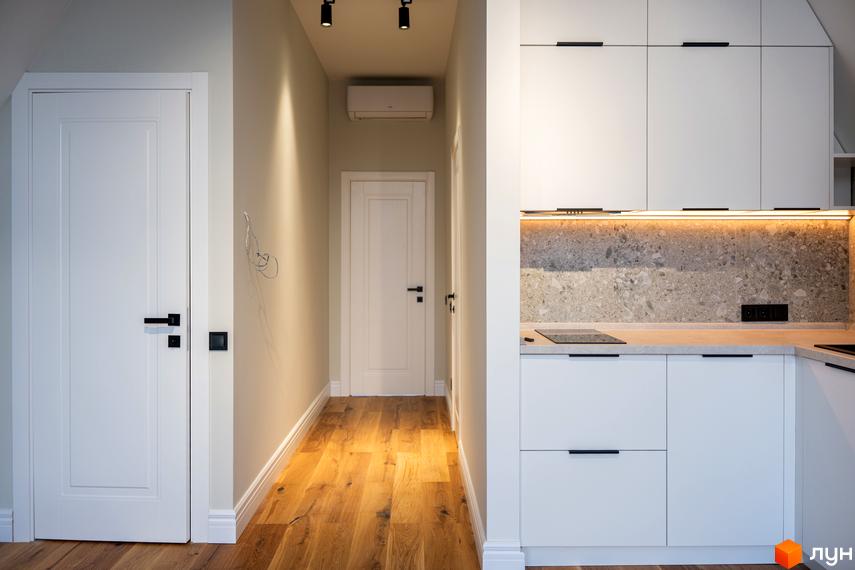 Інтер'єр квартири в житловому комплексі AMA FAMILY RESORT з білими дверима, дерев'яною підлогою та сучасною кухнею.