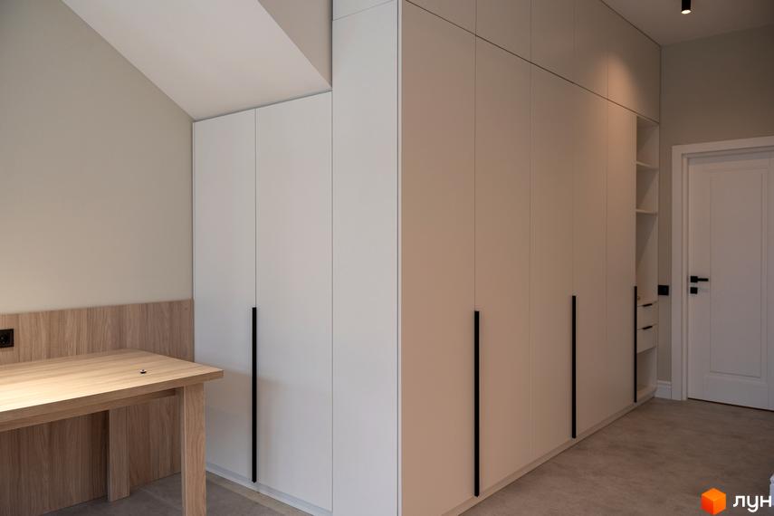 Сучасний інтер'єр спальні з великою шафою та письмовим столом у світлих тонах. AMA FAMILY RESORT - новий житловий комплекс для комфортного життя.