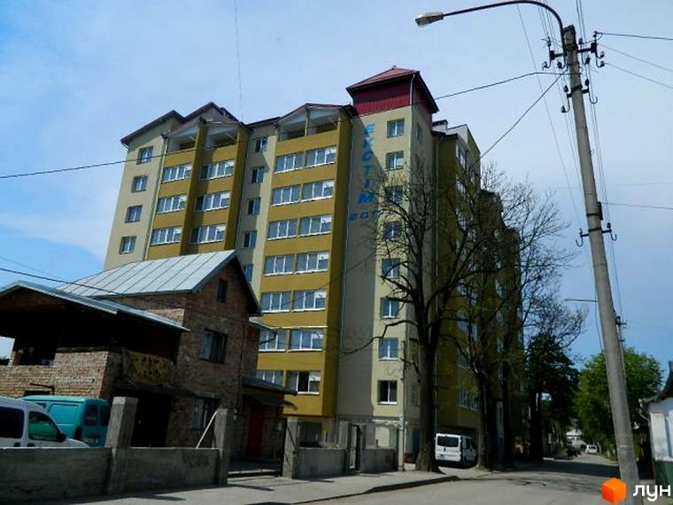 Зовнішній вигляд будинку на вулиці Ольги Кисілевської, 10. Багатоповерхова будівля з жовтим фасадом та великою кількістю вікон.