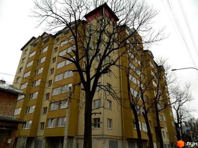 Фото фасаду будинку по вул. Ольги Кисілевської, 10. Багатоповерхова будівля з великими вікнами та деревами на передньому плані.