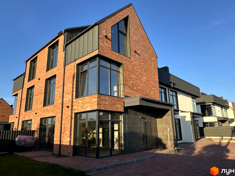 Таунхауси Lagom House з цегляним фасадом та великими вікнами, розташовані на вимощеній бруківкою території з доглянутим газоном.