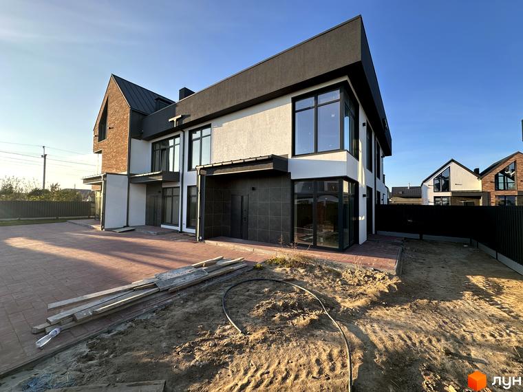 Таунхауси Lagom House з цегляним фасадом та великими вікнами. На прибудинковій території викладена бруківка та пісок.