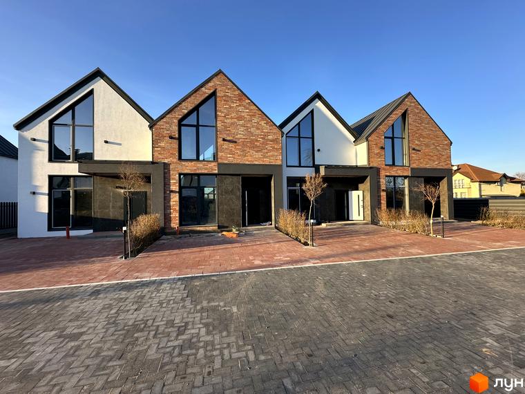 Таунхауси Lagom House з цегляним та білим фасадом, великими вікнами та бруківкою перед будинками.