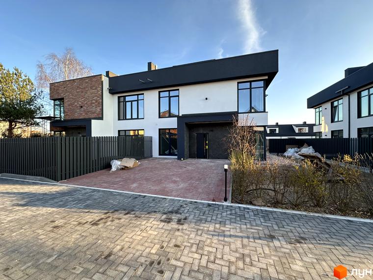 Зовнішній вигляд таунхаусів Lagom House з цегляним фасадом та великими вікнами. Прибудинкова територія з бруківкою та огорожею.