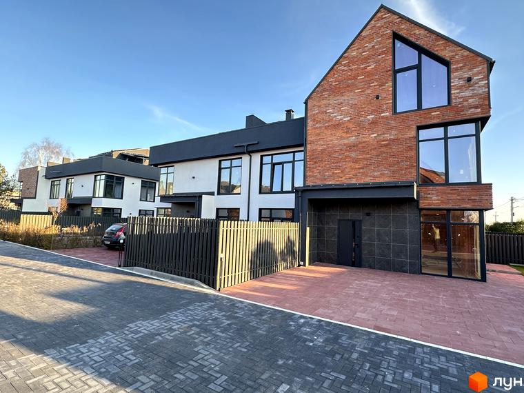 Зовнішній вигляд таунхаусів Lagom House з червоної цегли та білої штукатурки, з великими вікнами та парканом. Прибудинкова територія з бруківки та червоної плитки.