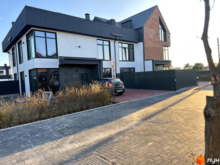 Таунхауси Lagom House - двоповерхові будинки з цегляним фасадом та білими стінами, огороджена територія з бруківкою та зеленими насадженнями.