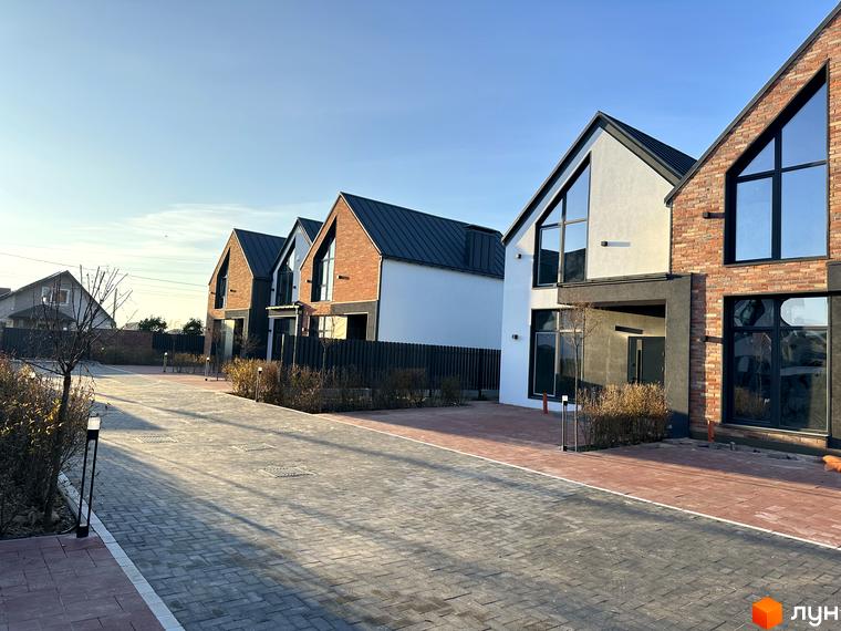 Таунхауси Lagom House з цегляним та білим оздобленням фасадів, великими вікнами та темними дахами. Повністю облаштована прибудинкова територія з бруківкою та освітленням.