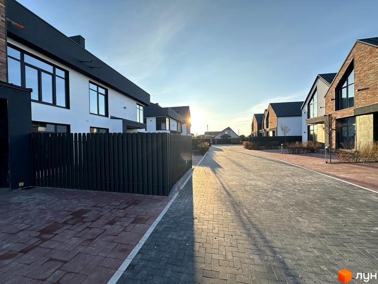 Таунхауси Lagom House з білою та цегляною обробкою фасадів, розташовані на вимощеній вулиці з бруківки.