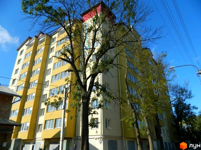 Зображення фасаду будинку на вулиці Ольги Кисілевської, 10. Багатоповерхова будівля з жовтими та білими стінами, велика кількість вікон.