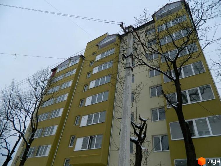 Зображення фасаду будинку на вулиці Ольги Кисілевської, 10. Багатоповерхова будівля з великими вікнами та деревами навколо.