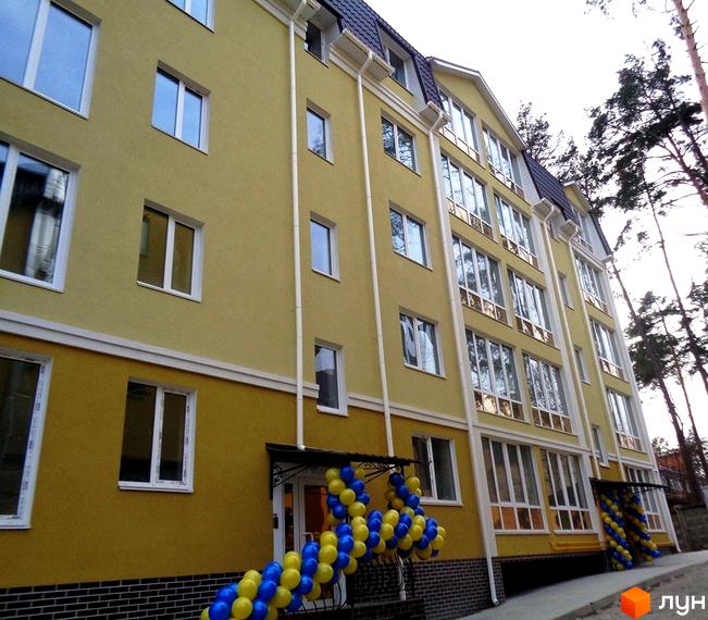 Зовнішній вигляд Житлового комплексу Пушкінський. Багатоповерховий будинок жовтого кольору з великою кількістю вікон та прикрасами з повітряних кульок.