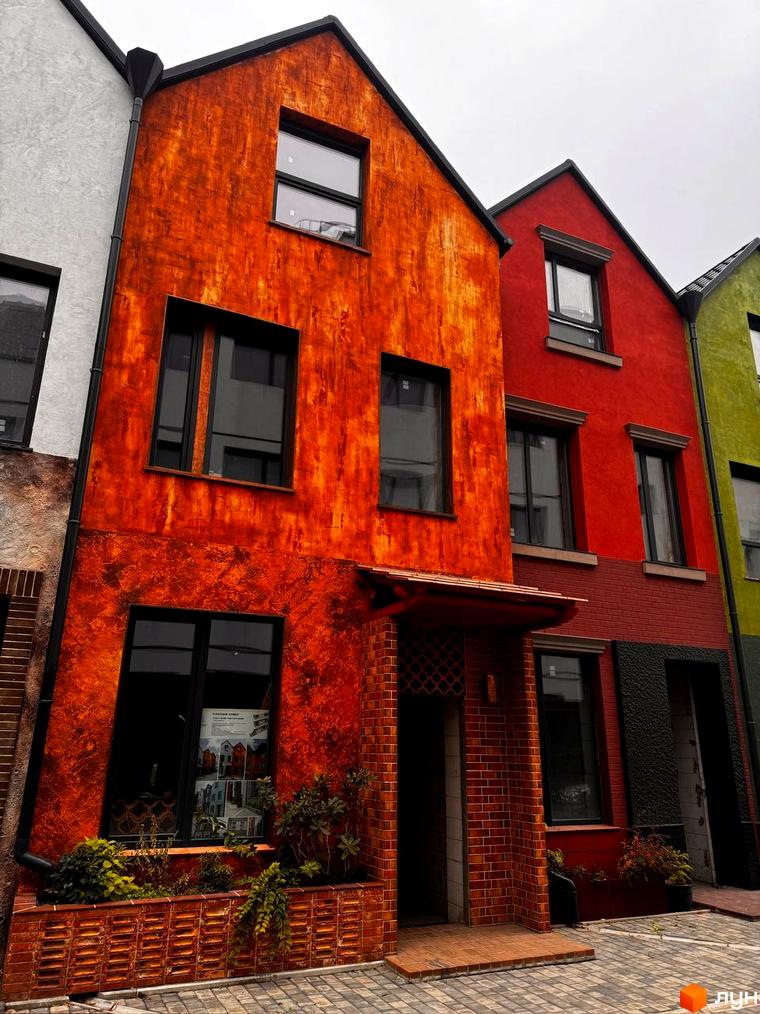 Яскраві фасади будинків житлового комплексу КМ KADENYUK homes. Зовнішній вигляд новобудов з цегляною кладкою та зеленими насадженнями.
