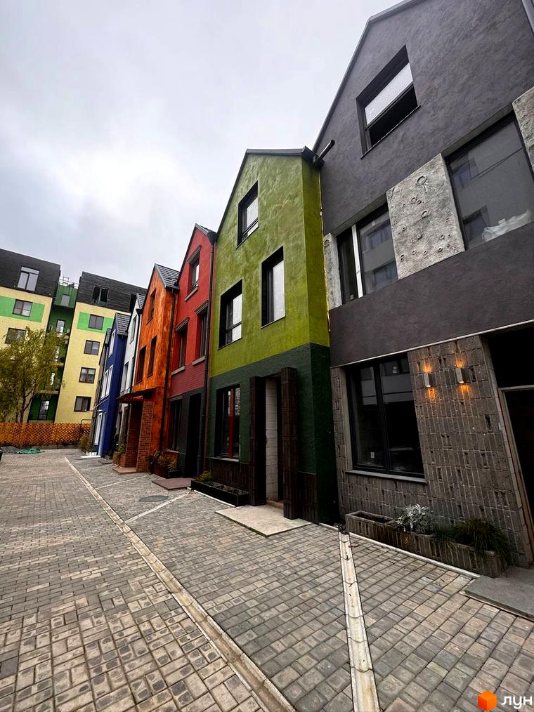 Котеджне містечко КАDЕНЮК homes: яскрава фасадна група будинків та вимощена бруківкою прибудинкова територія.