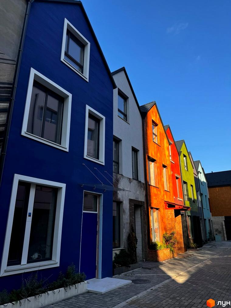 Котеджне містечко KADENYUK homes: фасади будинків у яскравих кольорах, вимощені вулиці та зелені насадження.