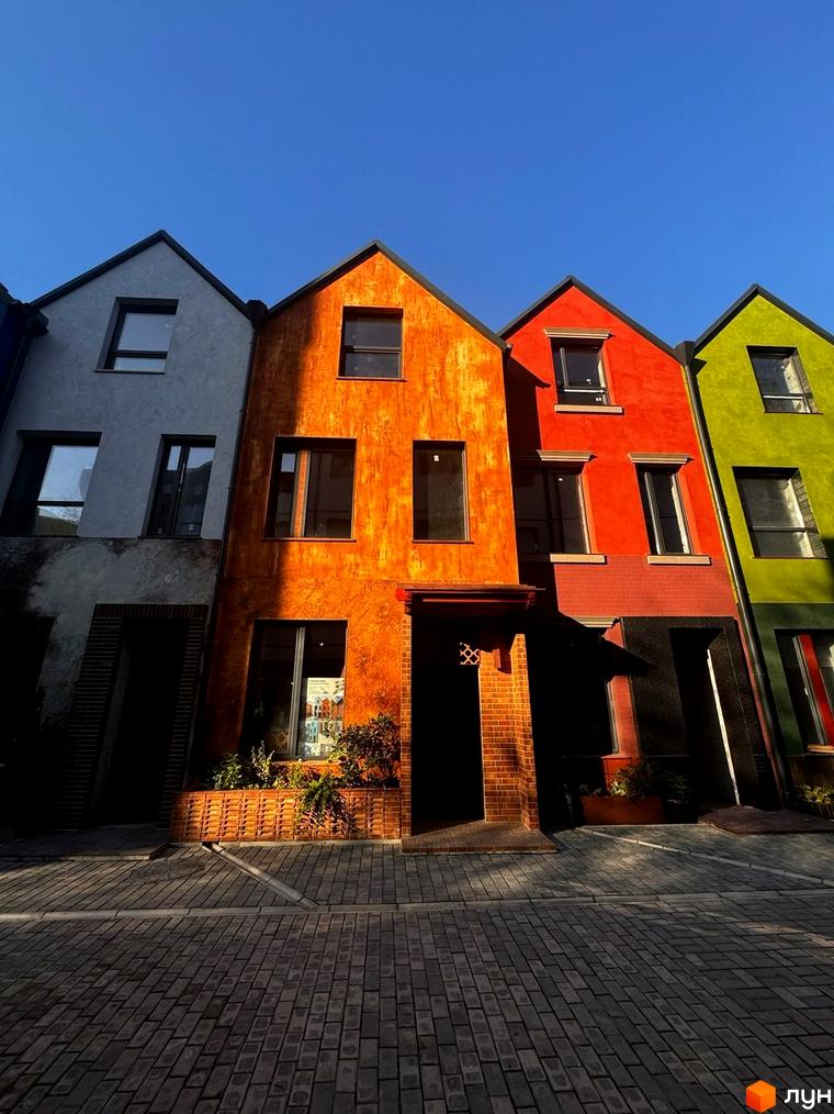 Котеджне містечко КАDЕНЮК homes: яскраві фасади будинків та брукована прибудинкова територія під блакитним небом. Ознайомтеся з плануваннями та цінами.