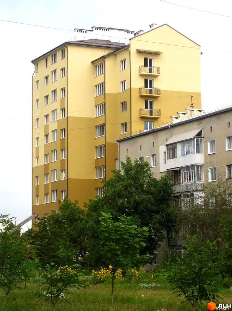 Фото багатоповерхового будинку на вулиці Івана Драча (Радіщева). Вигляд фасаду та прибудинкової території з деревами.