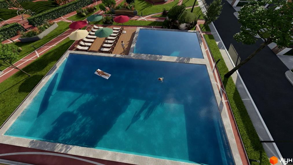 Огляд території Котеджного містечка Smaragd town з басейном, шезлонгами та парасольками. На території комплексу є зелені насадження та доріжки.