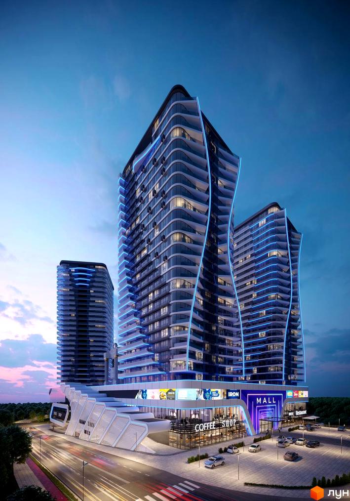 Житловий комплекс Aura city з футуристичною архітектурою та блакитною підсвіткою. Навколо комплексу розташовані торговельний центр, парковка та дорога з автомобілями.