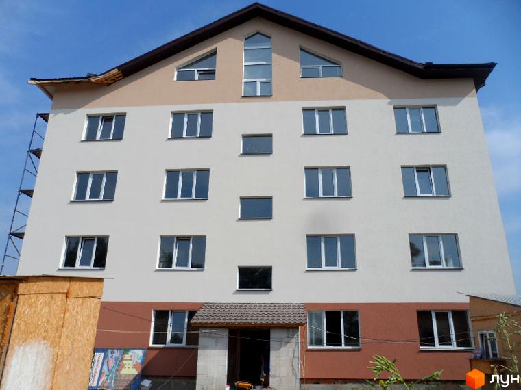Зовнішній вигляд будинку в Житловому комплексі Фізкультурний. Багатоповерхова будівля з великими вікнами та коричневим дахом.