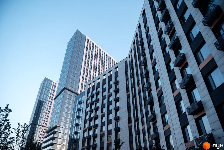 Фасад житлового комплексу Метрополіс з численними вікнами та балконами. Сучасна архітектура новобудови на фоні блакитного неба.