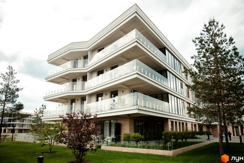 Житловий комплекс Park Lake City із сучасними балконами та скляними огорожами. Навколо будинку зелена галявина та дерева.