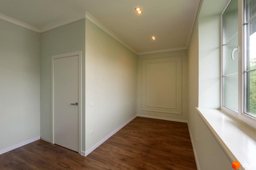 Клубний будинок „Кагарлицький“: світла кімната з дверима та вікном, дерев'яна підлога та декоративні елементи на стінах.