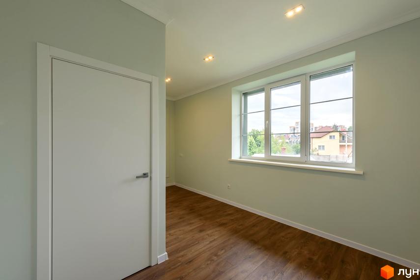 Світла кімната в Клубний будинок „Кагарлицький“ з пастельними стінами, дерев'яною підлогою та великим вікном, що виходить на міський пейзаж.