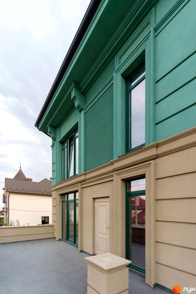 Фасад Таунхаус Green Life виконаний у зелених та бежевих тонах з декоративними елементами. Перед будинком розташована простора тераса з сірою плиткою.